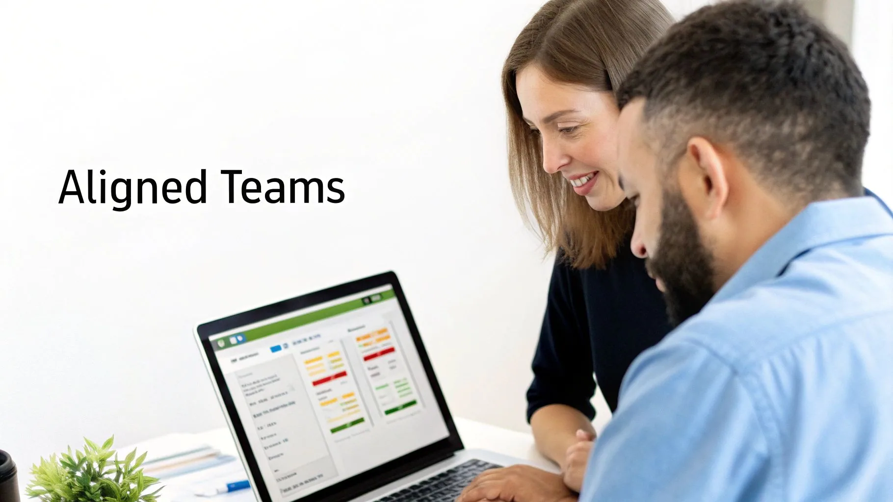 Two colleagues, a man and a woman, smilingly collaborate over a laptop showing "Aligned Teams" data.