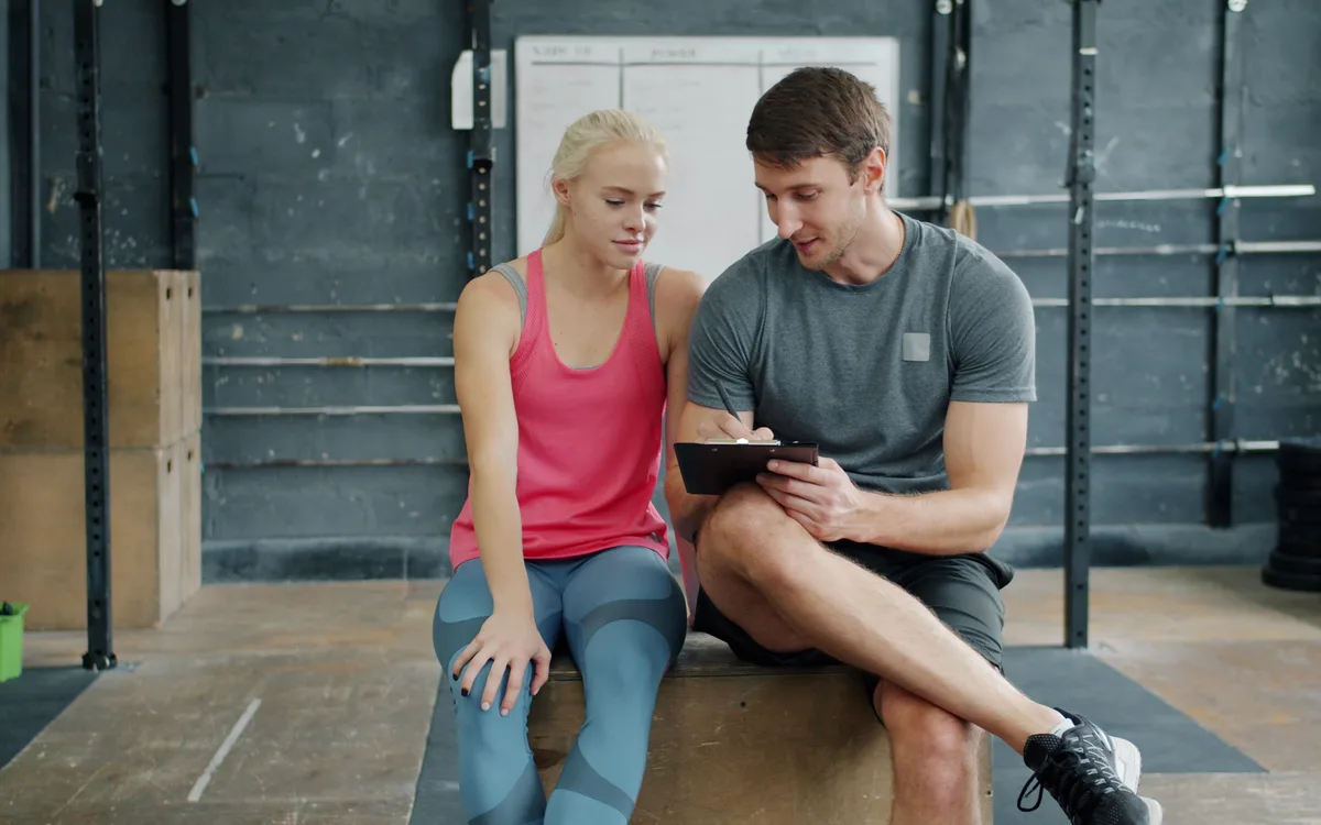 Illustrative stock: A personal trainer discussing a workout with a club member
