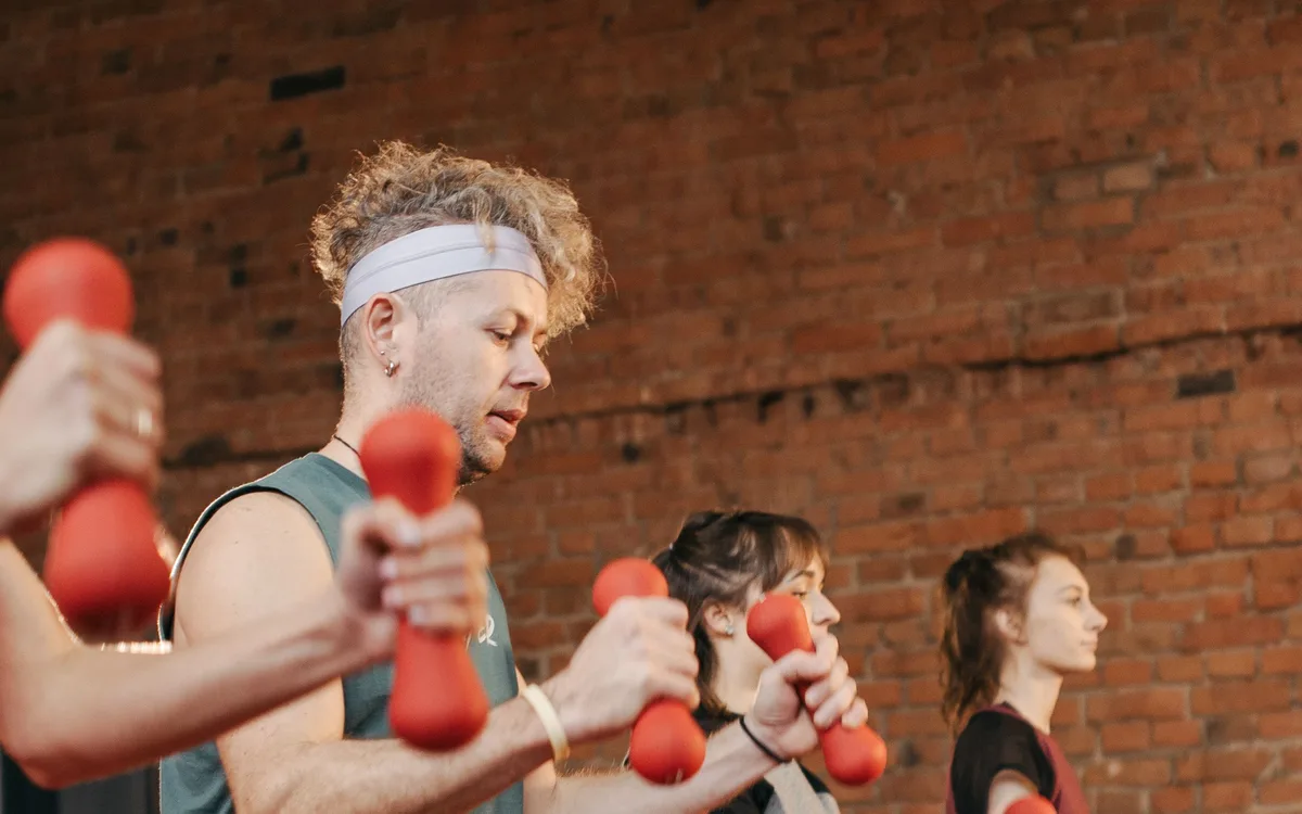 Illustrative stock: Health club members training with dumbbells